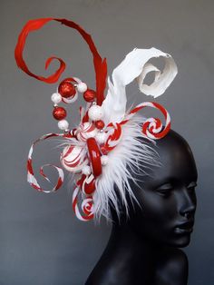 a red and white headpiece with feathers on top of a mannequin's head