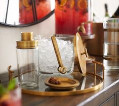 an assortment of glass and metal items on a table with a clock in the background