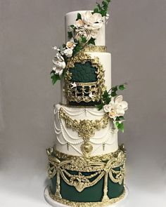 a three tiered cake with gold and green decorations