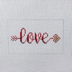 the word love is written in red thread on a white background with an arrow pointing to it