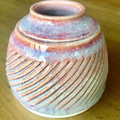 a brown and white vase sitting on top of a wooden table