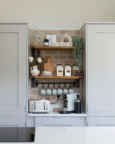 a kitchen with white cabinets and shelves filled with coffee pots, tea kettles and other items