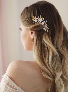 a woman with long hair wearing a gold and white flower headpiece in front of a window