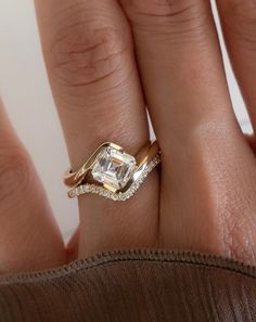 a woman's hand with a diamond ring on top of her finger and an engagement band