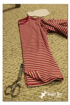 a pair of scissors laying on top of a red and white stripped scarf