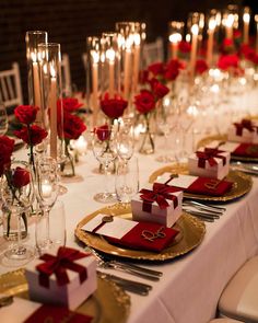 the table is set with red roses and place settings for guests to sit down at