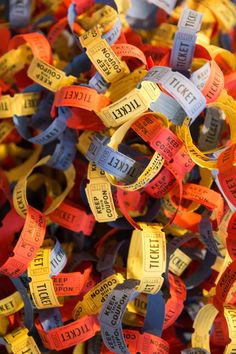 many different colored wristbands with words written on them are stacked together in the shape of rings