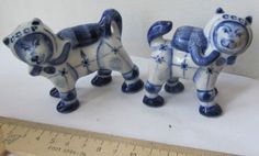 two blue and white ceramic dogs next to a ruler