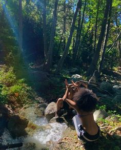 a woman sitting on top of a rock next to a river