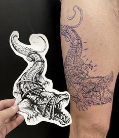 a man with a tattoo on his arm holding up a sticker that looks like a lizard