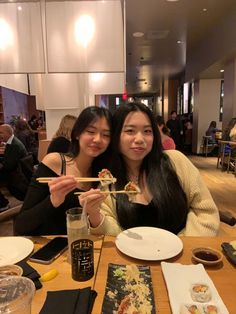 two women sitting at a table eating sushi