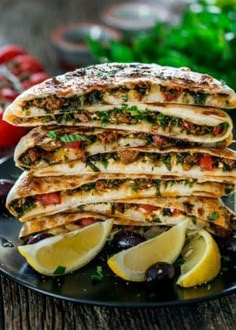 a stack of quesadillas on a plate with lemons and olives