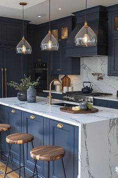 a kitchen with blue cabinets and marble counter tops, gold accents and pendant lights hanging from the ceiling