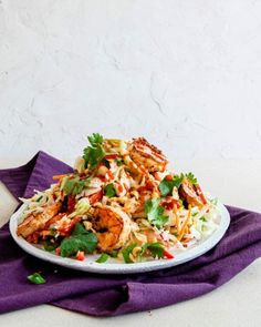 a white plate topped with shrimp and coleslaw salad next to a purple napkin