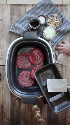 hamburger patties in an air fryer on a wooden table with other food items