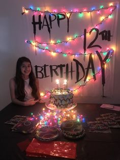 a woman sitting in front of a birthday cake with lite up lights on it