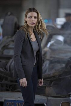 a woman standing in front of a wrecked car