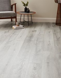 a living room with grey wood floors and white walls