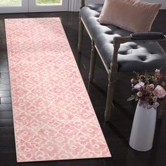 a living room with a pink rug on the floor next to a chair and window