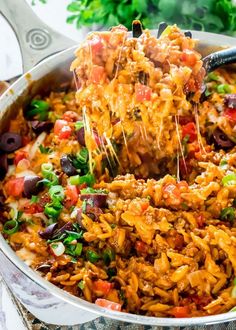 a large pot full of mexican rice and vegetables being lifted with a ladle from it