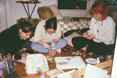 three women are sitting on the floor looking at pictures