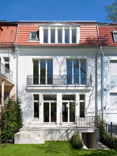 a large white house with red tiled roof and balconies on the second floor