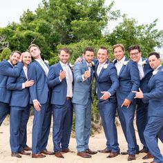 a group of men standing next to each other wearing blue suits and white shirts with their arms in the air