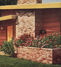 a brick house with flowers in the front and side flower boxes on the outside wall