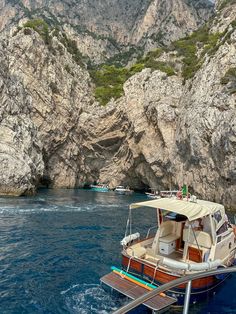 a small boat in the water near some mountains and cliffs with people standing on it