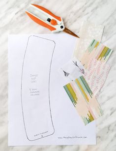 scissors, paper and other crafting supplies on a marble counter top with the cut out pattern