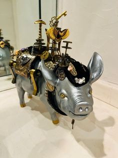 a sculpture of an elephant with gold and silver decorations on it's back, in front of a mirror