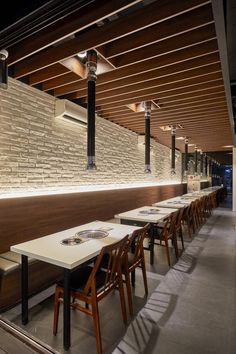 an empty restaurant with tables and chairs lined up against the wall, along with exposed lighting