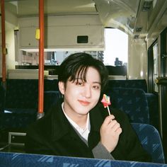 a young man holding a lollipop in his hand on a public transit bus