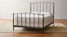 an iron bed frame with white sheets and pillows