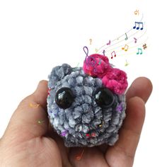 a hand holding a small stuffed animal with musical notes coming out of it's eyes