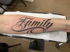 a person with a tattoo on their arm that says family in cursive writing