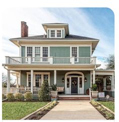 a green house with white trim on the front porch and second story balcony above it