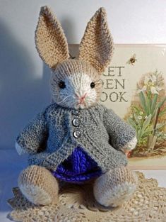 a crocheted bunny sitting on top of a doily next to a book