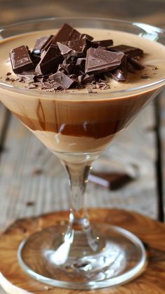 a chocolate dessert in a glass on top of a wooden table