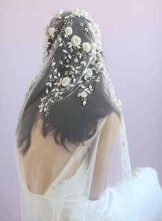 the back of a woman's head wearing a veil with white flowers on it