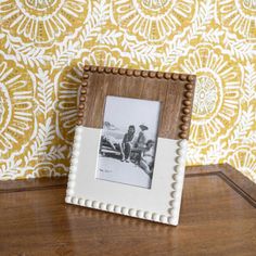 an old photo frame sitting on top of a wooden table next to a wallpaper