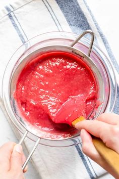 someone using a brush to dip something red in the bowl