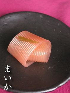 a piece of sushi sitting on top of a black plate with writing in japanese