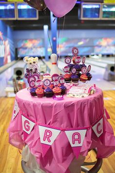 a bowling alley filled with lots of pink and white decorations on top of a table