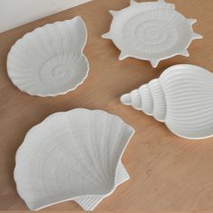 three white seashells sitting on top of a wooden table