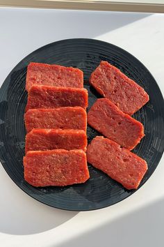 four pieces of raw meat on a black plate