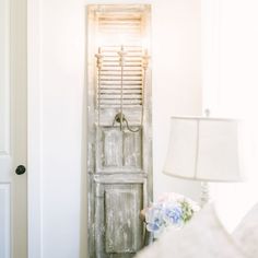 a room with a bed, lamp and shuttered door in it's corner