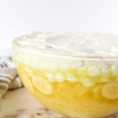 a glass bowl filled with bananas and whipped cream on top of a marble countertop