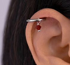 a woman's ear with a small red stone on it