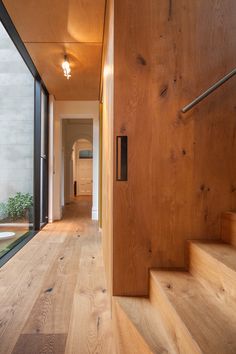 an empty hallway with wooden steps leading up to the door and windows on both sides